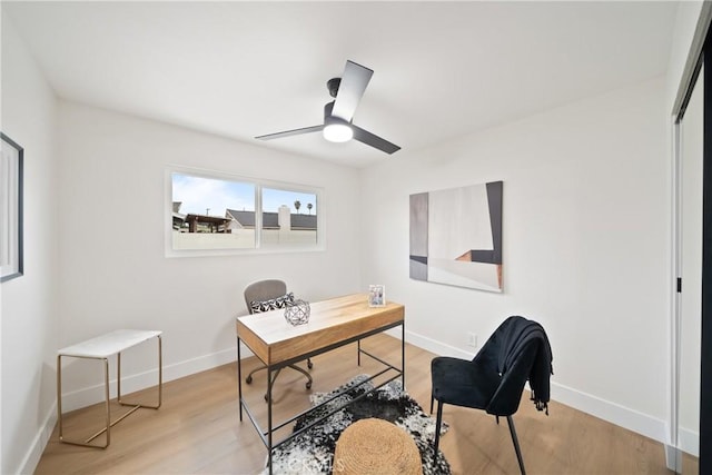office space featuring baseboards, ceiling fan, and light wood finished floors