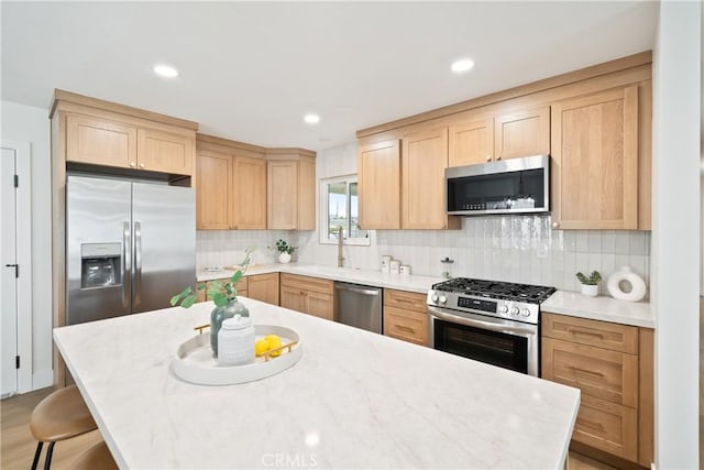 kitchen featuring decorative backsplash, light brown cabinetry, light countertops, a sink, and stainless steel appliances