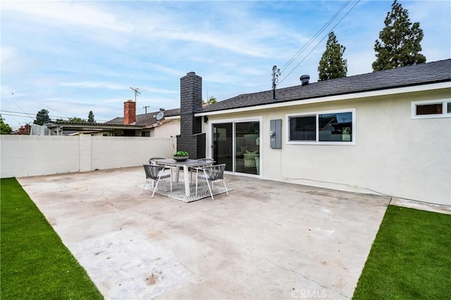 back of house with fence, a patio, stucco siding, and a chimney