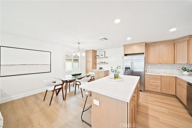 kitchen with light brown cabinets, a kitchen island, stainless steel appliances, and visible vents
