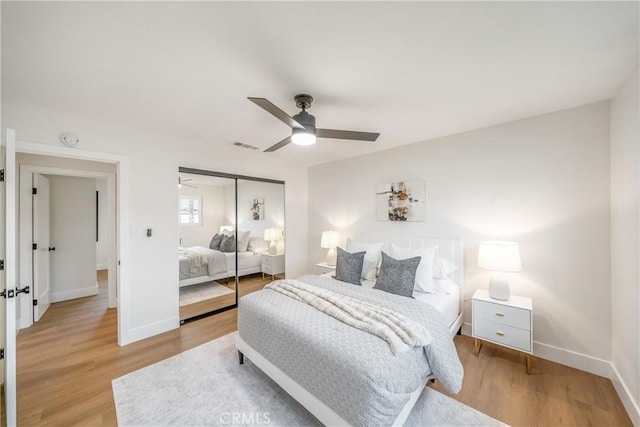 bedroom with visible vents, a closet, light wood-style floors, baseboards, and a ceiling fan