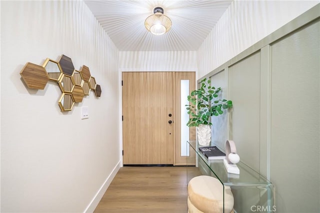 doorway to outside with baseboards and wood finished floors