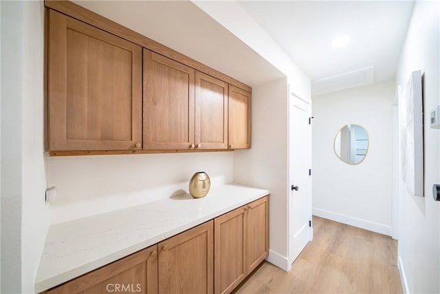 laundry area featuring baseboards, attic access, and light wood-type flooring