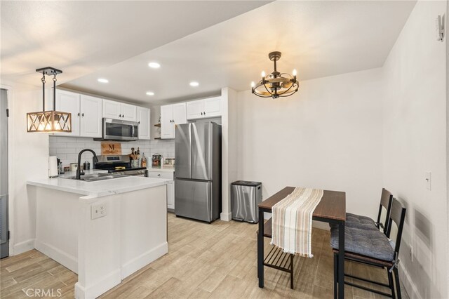 2265 Bradford Ave Unit 516, Highland, CA 92346 - kitchen featuring stainless steel appliances, a chandelier, a peninsula, light wood-style flooring, and a sink
