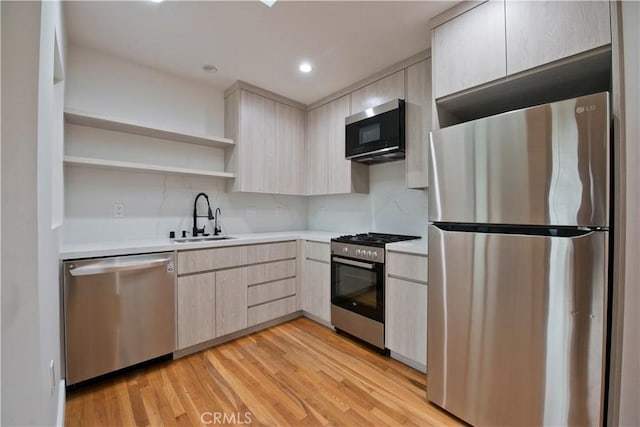 kitchen with light brown cabinetry, a sink, open shelves, light countertops, and appliances with stainless steel finishes