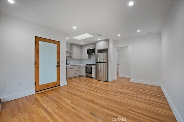 kitchen featuring open shelves, a skylight, stainless steel appliances, light countertops, and baseboards