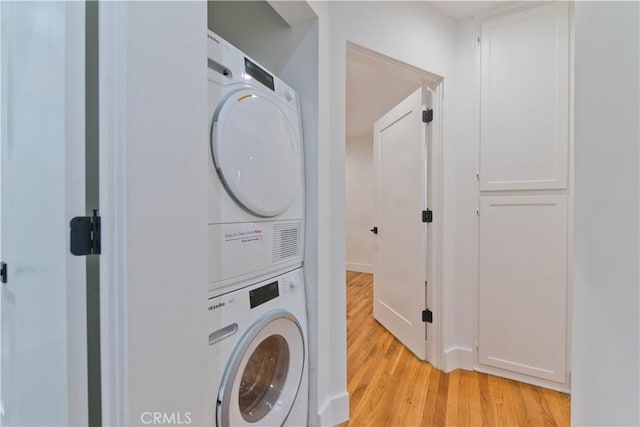 laundry room with light wood-style floors, stacked washer / dryer, and laundry area