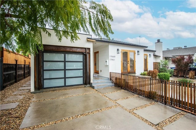 view of front of house with driveway, french doors, fence private yard, and a garage