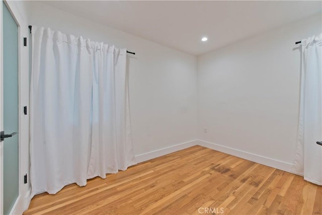 unfurnished room with baseboards, recessed lighting, and light wood-style floors