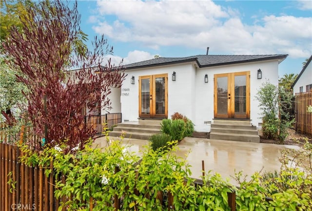 view of front of house with entry steps, french doors, and fence