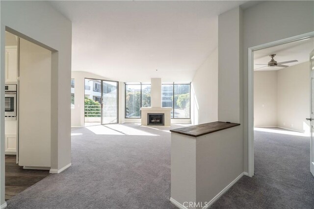 230 Lille Ln Unit 214, Newport Beach, CA 92663 - unfurnished living room with baseboards, a ceiling fan, carpet flooring, and a fireplace