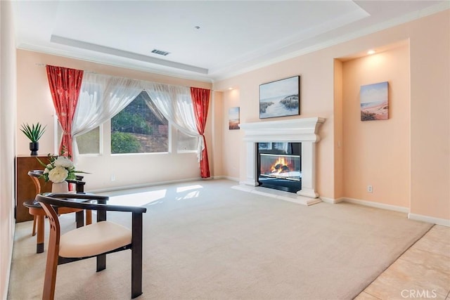 living area with visible vents, crown molding, baseboards, a glass covered fireplace, and carpet flooring