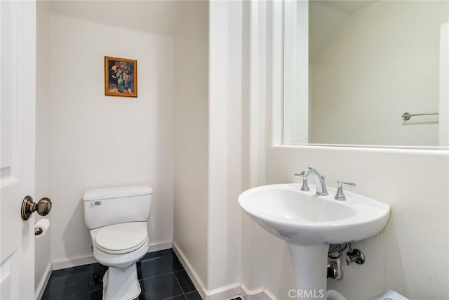 bathroom featuring baseboards, toilet, tile patterned floors, and a sink