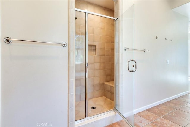 full bath featuring tile patterned floors, a shower stall, and baseboards