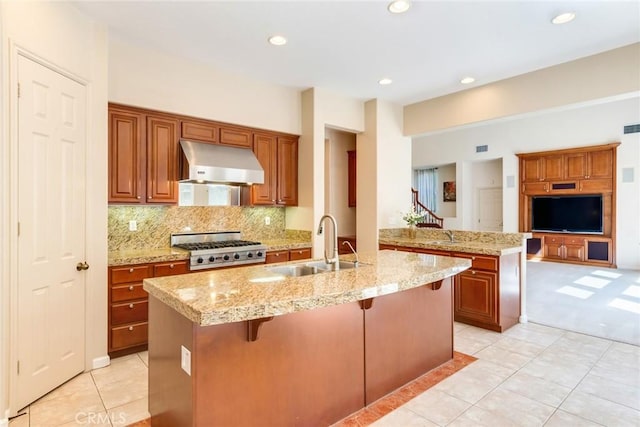 kitchen with light tile patterned flooring, stove, a breakfast bar area, under cabinet range hood, and a sink