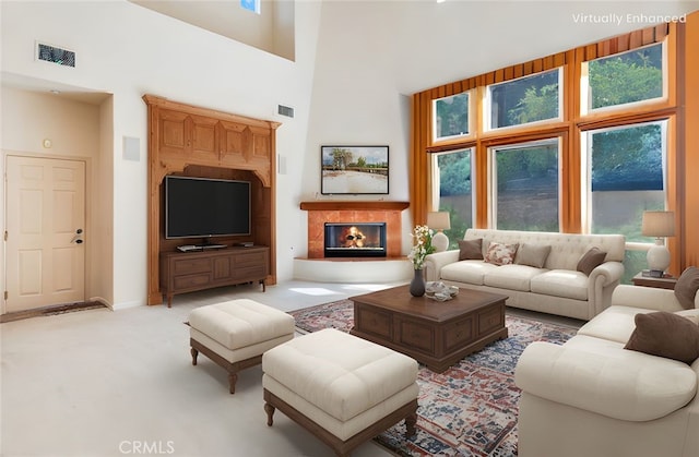 living room with light colored carpet, a high ceiling, visible vents, and a healthy amount of sunlight