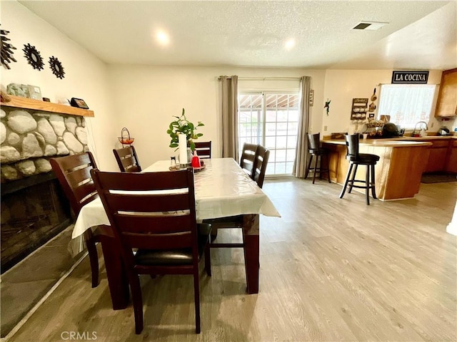 1078 W King St, Banning, CA 92220 - dining space featuring light wood-type flooring, a textured ceiling, and a fireplace