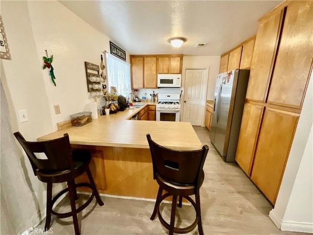 1078 W King St, Banning, CA 92220 - kitchen featuring a sink, visible vents, light countertops, white appliances, and a peninsula