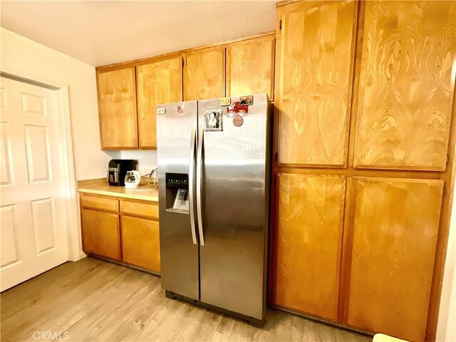 1078 W King St, Banning, CA 92220 - kitchen with stainless steel refrigerator with ice dispenser, light wood-style flooring, brown cabinetry, and light countertops