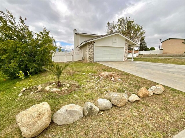 1078 W King St, Banning, CA 92220 - view of side of property featuring concrete driveway, stone siding, fence, a yard, and a garage
