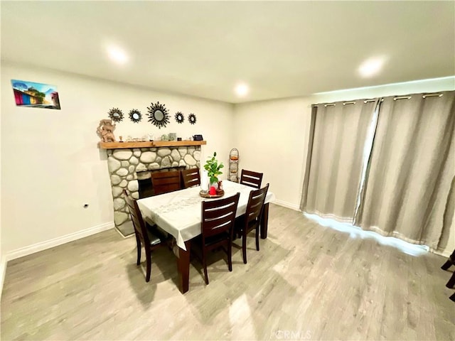 1078 W King St, Banning, CA 92220 - dining room with a fireplace, light wood-style flooring, and baseboards