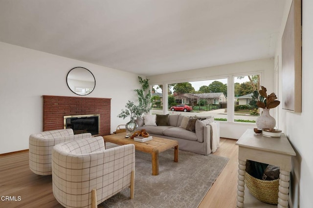 living area featuring a healthy amount of sunlight, a brick fireplace, and wood finished floors