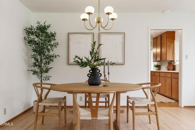 dining area with light wood finished floors, baseboards, and an inviting chandelier