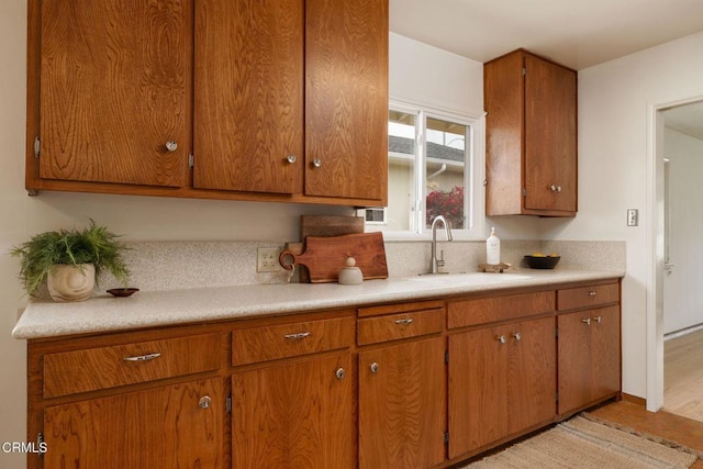 kitchen featuring light countertops, brown cabinetry, and a sink
