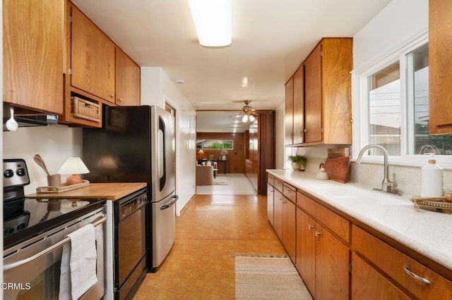 kitchen featuring light floors, light countertops, a sink, a wealth of natural light, and appliances with stainless steel finishes