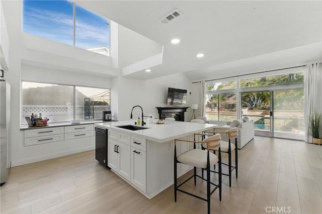 3381 Deaver Dr, Corona, CA 92882 - kitchen featuring white cabinets, a sink, light wood-style floors, a center island with sink, and a breakfast bar area
