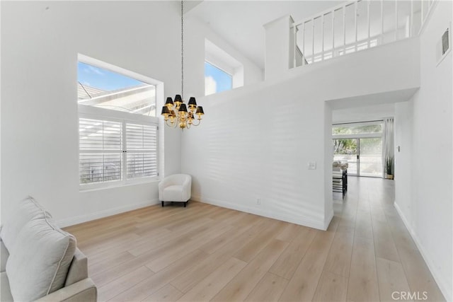3381 Deaver Dr, Corona, CA 92882 - living area with a high ceiling, light wood finished floors, visible vents, baseboards, and a chandelier