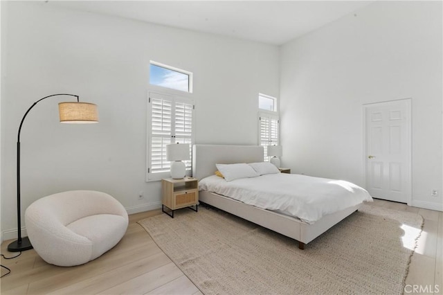3381 Deaver Dr, Corona, CA 92882 - bedroom with light wood-style floors, a towering ceiling, and baseboards