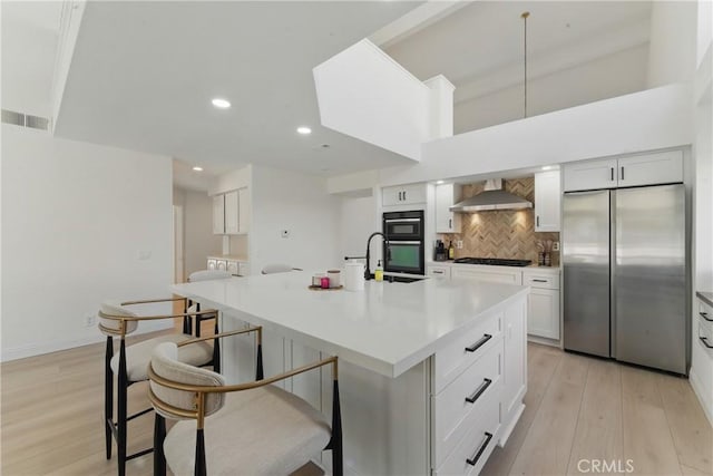 3381 Deaver Dr, Corona, CA 92882 - kitchen featuring wall chimney range hood, visible vents, a sink, stainless steel fridge, and gas stovetop