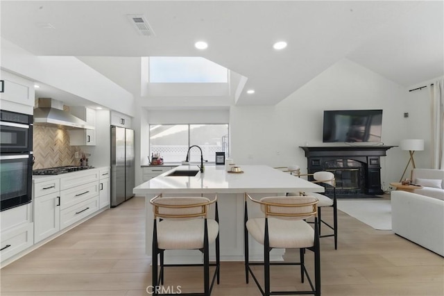 3381 Deaver Dr, Corona, CA 92882 - kitchen with wall chimney exhaust hood, freestanding refrigerator, a sink, and lofted ceiling