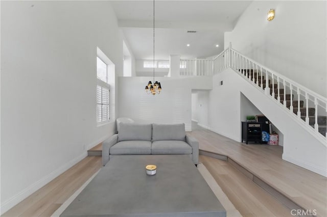 3381 Deaver Dr, Corona, CA 92882 - living room with wood finished floors, stairs, an inviting chandelier, a towering ceiling, and baseboards