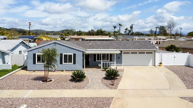 ranch-style home featuring a gate, driveway, fence, a mountain view, and a garage