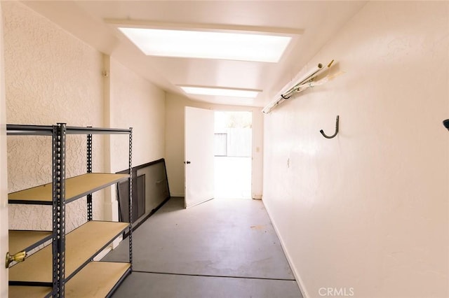 hall featuring baseboards and finished concrete flooring