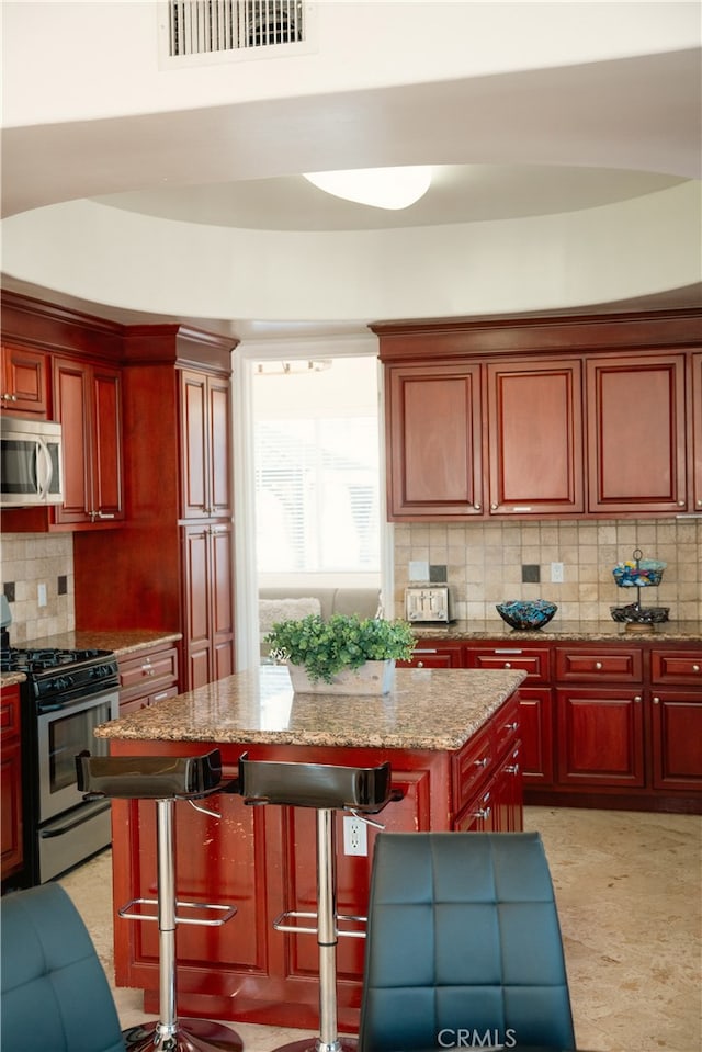 11310 Wentworth St, Sun Valley, CA 91352 - kitchen featuring a center island, dark brown cabinets, visible vents, decorative backsplash, and appliances with stainless steel finishes