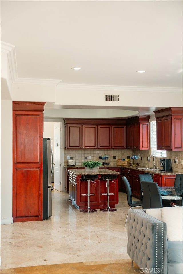 11310 Wentworth St, Sun Valley, CA 91352 - kitchen featuring freestanding refrigerator, visible vents, backsplash, reddish brown cabinets, and a breakfast bar