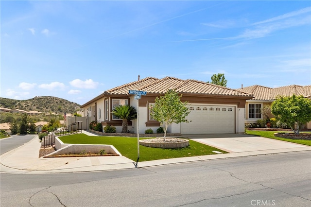 6112 Turnberry Dr, Banning, CA 92220 - mediterranean / spanish home with a tiled roof, driveway, fence, an attached garage, and stucco siding