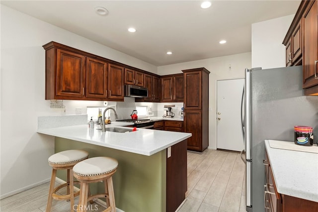6112 Turnberry Dr, Banning, CA 92220 - kitchen with a peninsula, a breakfast bar area, light countertops, a sink, and appliances with stainless steel finishes