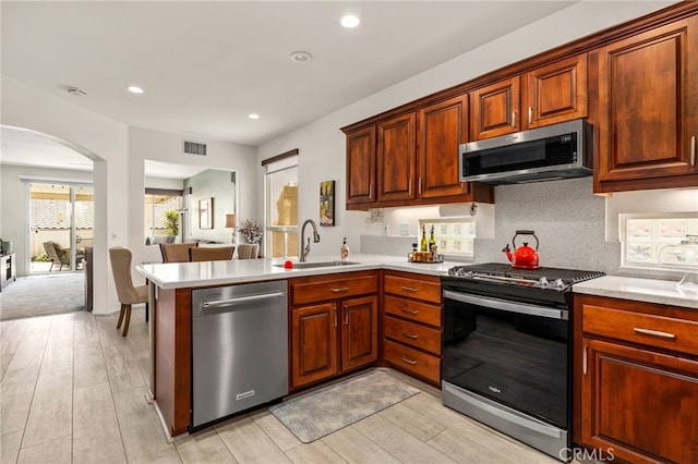 6112 Turnberry Dr, Banning, CA 92220 - kitchen with appliances with stainless steel finishes, a sink, light countertops, arched walkways, and a peninsula