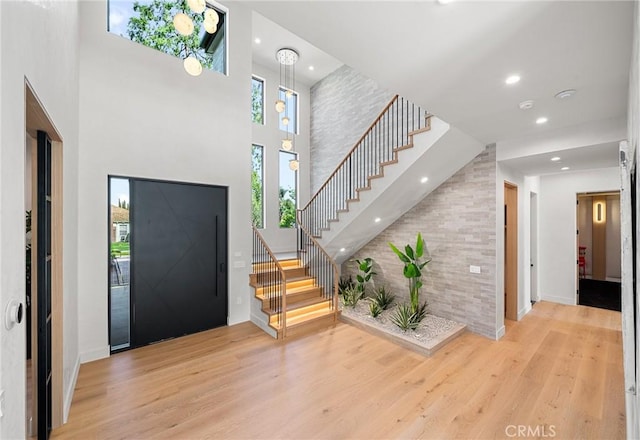 foyer featuring recessed lighting, a high ceiling, wood finished floors, baseboards, and stairs