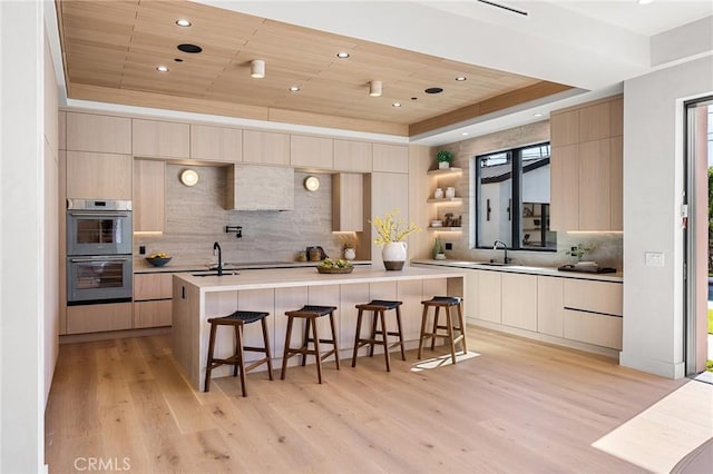 kitchen featuring modern cabinets, backsplash, double wall oven, and a sink