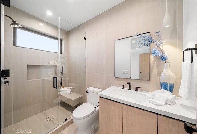 bathroom with tile patterned floors, a stall shower, vanity, tile walls, and toilet