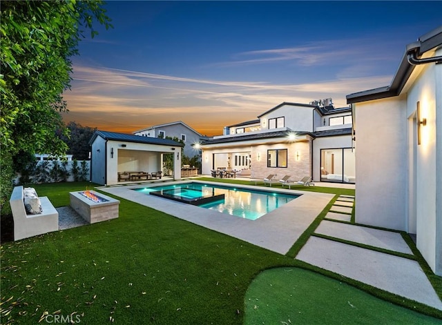rear view of house featuring a patio area, an outdoor structure, a yard, stucco siding, and a pool with connected hot tub