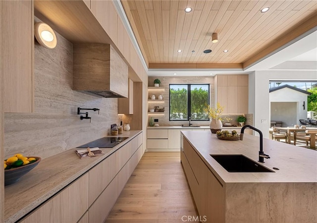 kitchen featuring light wood finished floors, wooden ceiling, a sink, modern cabinets, and tasteful backsplash