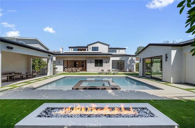 back of house with a patio area, stone siding, an outdoor living space with a fire pit, stucco siding, and a pool with connected hot tub