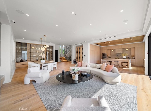 living room with recessed lighting, light wood-type flooring, and stairs