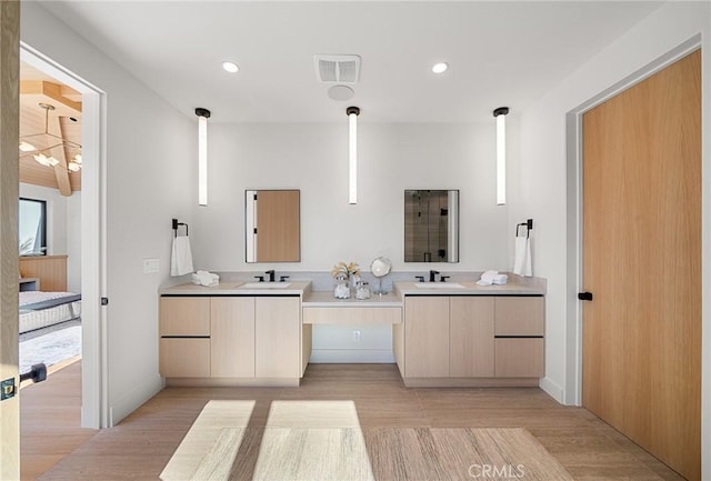 ensuite bathroom featuring recessed lighting, double vanity, and wood finished floors